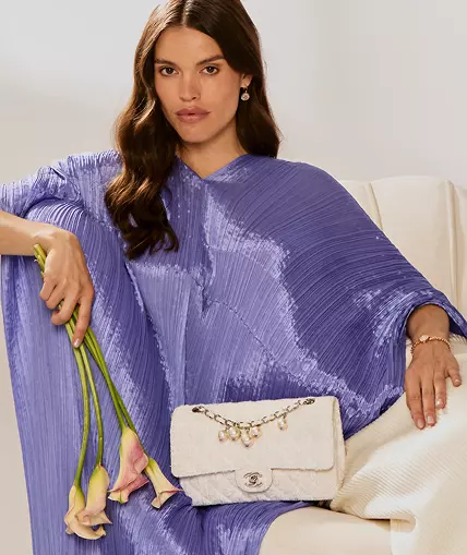 Hero Banner: A model in a purple Issey Miyake top with a white tweed Chanel double flap bag on her lap.