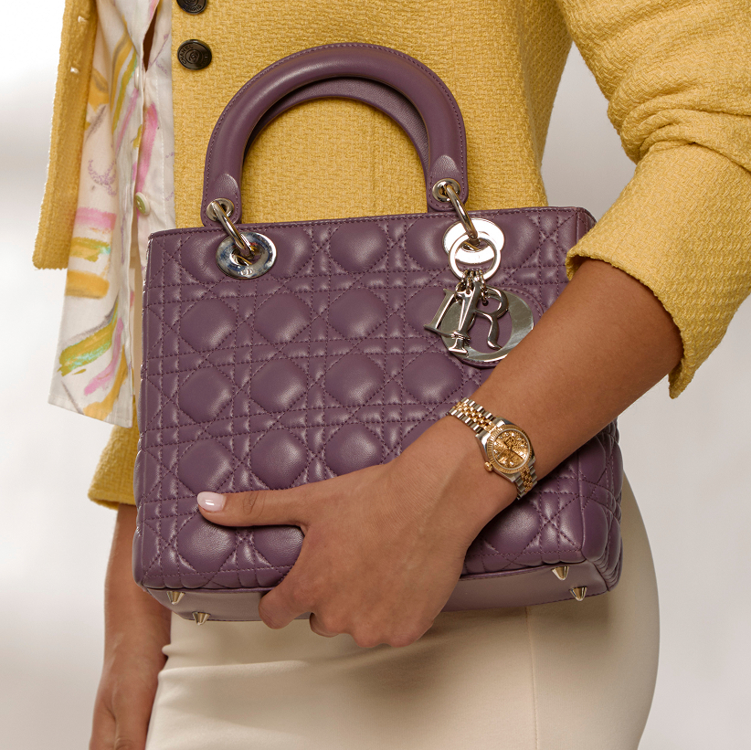 Watch Feature: A model holding a Dior Lady Dior bag in purple leather wearing a Rolex watch 