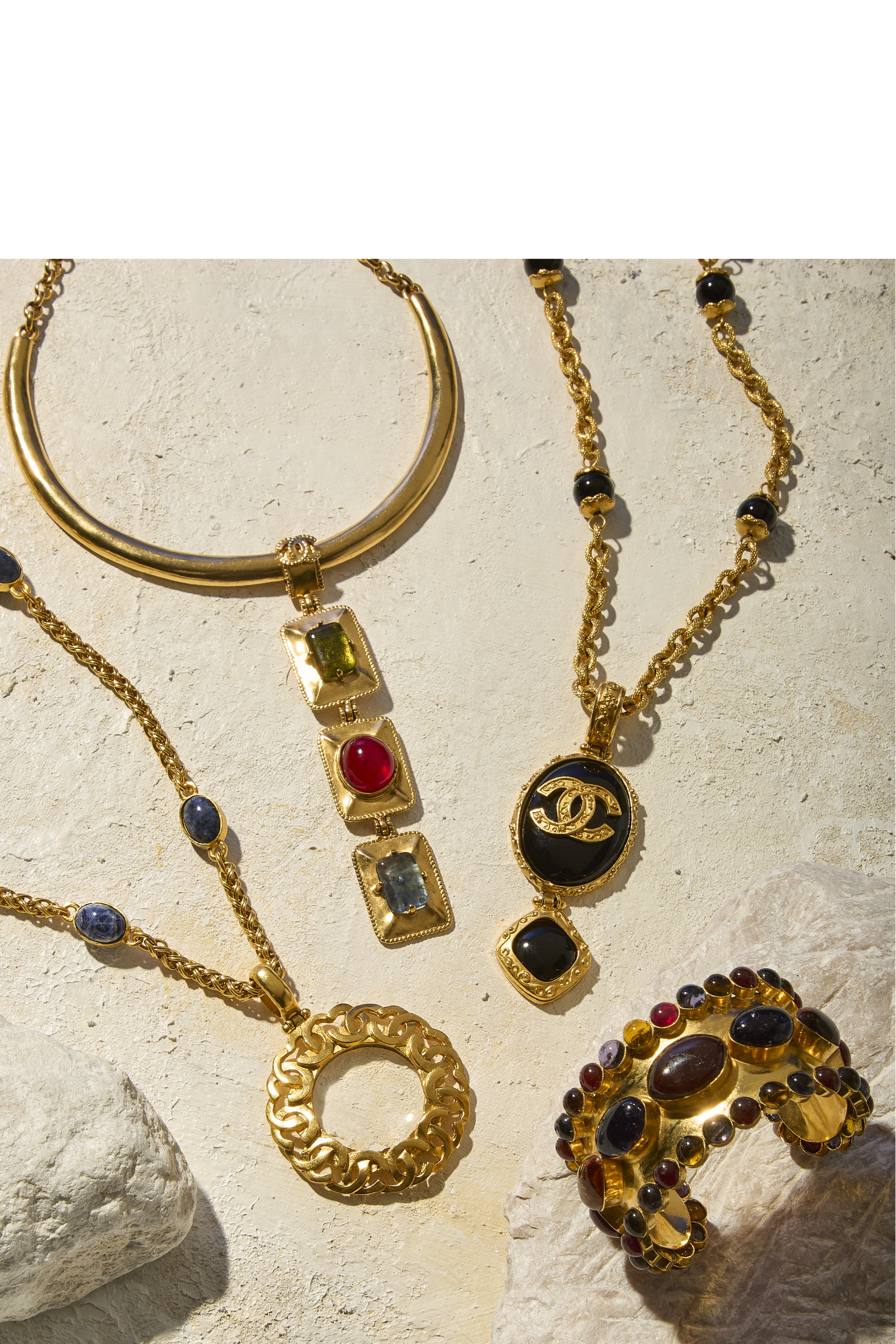 Hero Banner: A model wearing Chanel gripoix earrings and cuff and Chanel gripoix pieces laid out on stone.